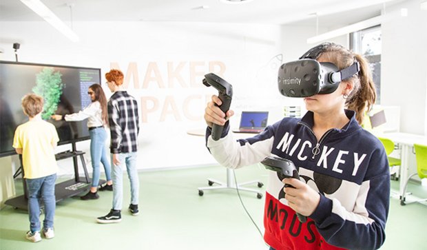 Student using a VR headset while classmates work in a flexible learning space