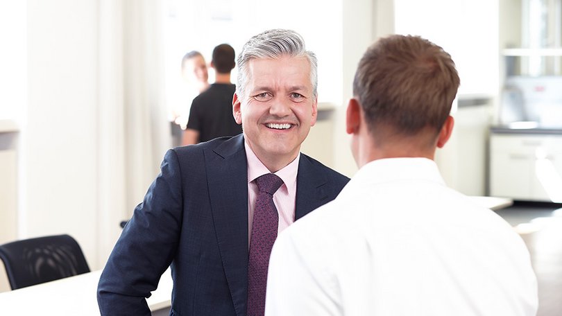Zwei Männer schauen gemeinsam auf einen Laptop im Büro
