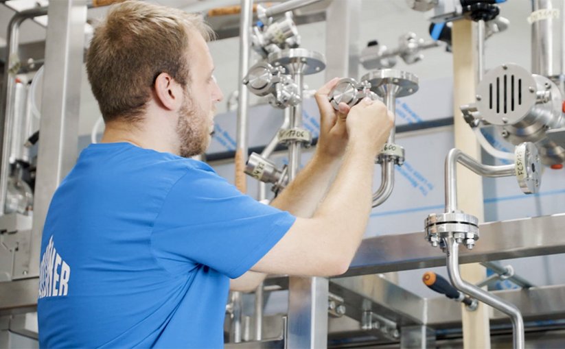 Person inspects valve on stainless steel system