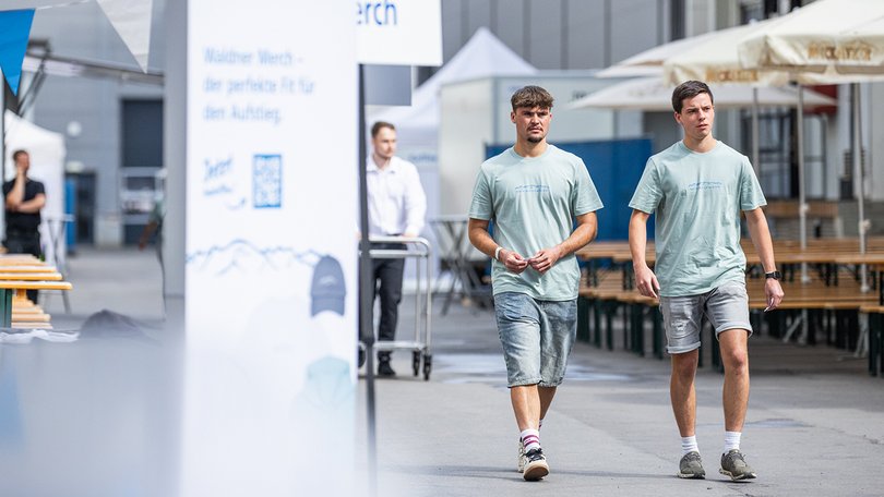 Zwei Personen laufen am Merchandise-Stand vorbei