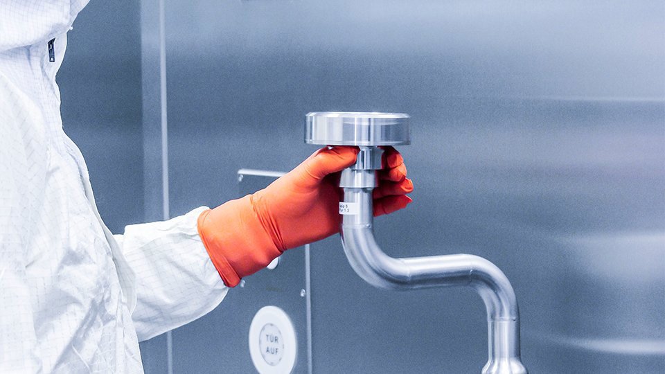 Person bedient Edelstahlventil mit rotem Handschuh