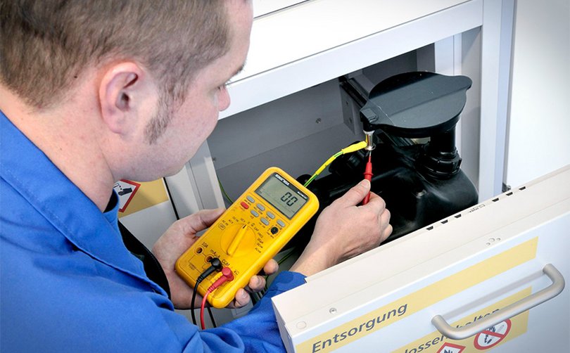 Person misst Spannung an Sicherheitsschrank