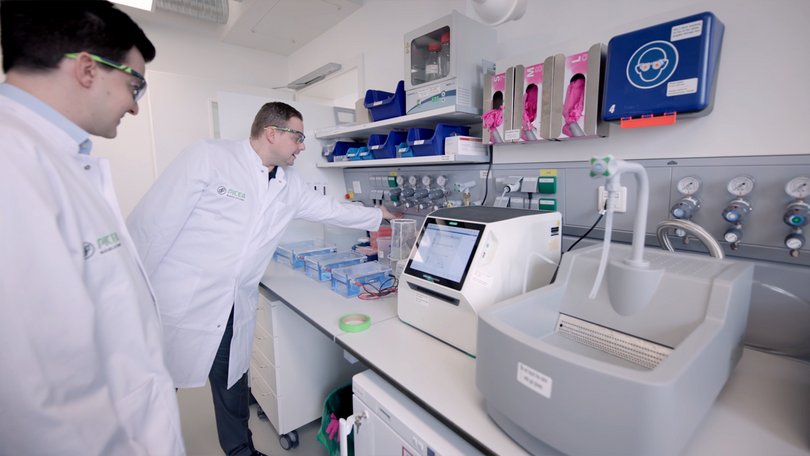 Zwei Labormitarbeiter führen Analyse an einem Laborgerät durch.