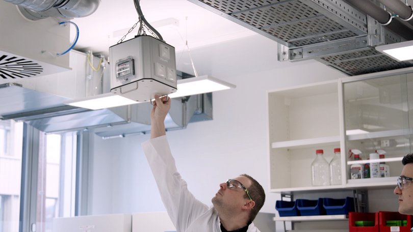 Laborant justiert Deckenversorgungssystem im Labor.