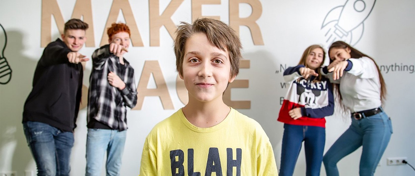 Group of students posing confidently in front of a makerspace wall
