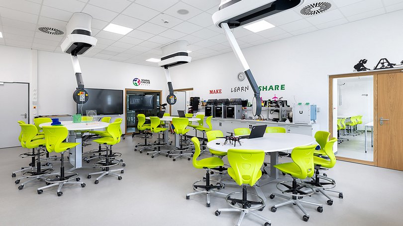 Bright makerspace classroom with green chairs and Fly One systems