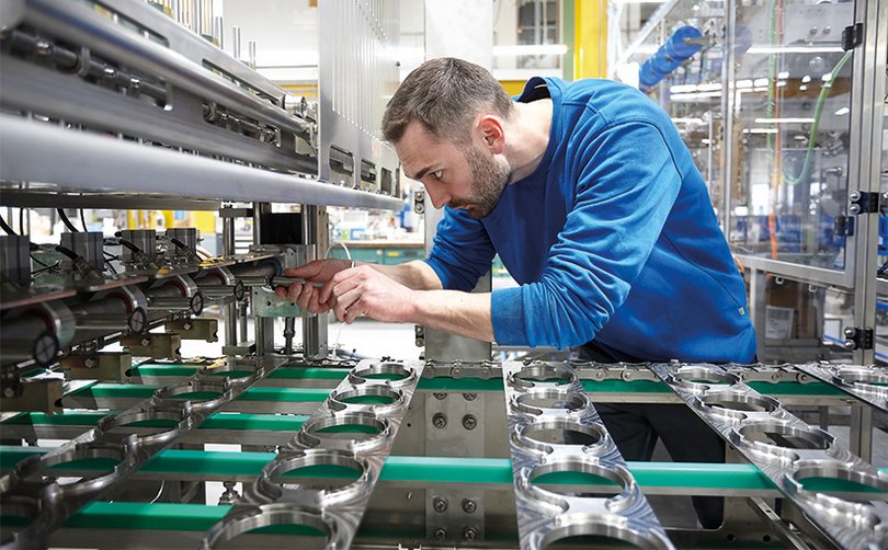 Mitarbeiter kontrolliert Bauteile in einer Produktionsanlage.