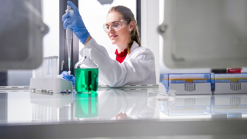 Laboratory staff with pipette working near lab fume hood