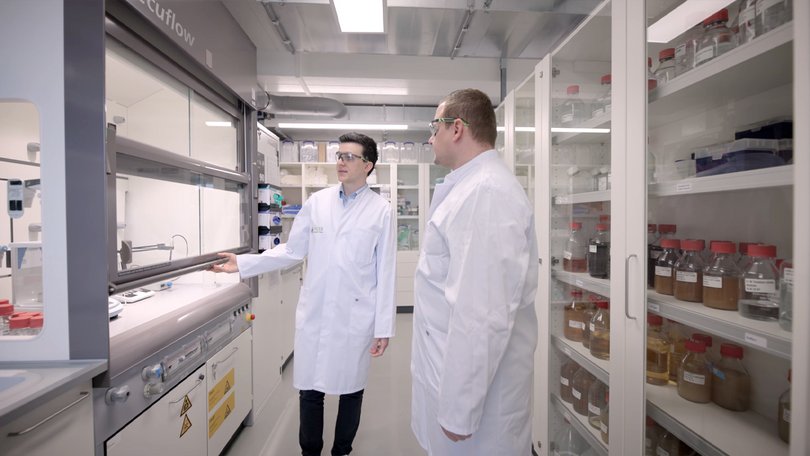 Zwei Personen besprechen Arbeitsschritte an einem Laborarbeitsplatz.