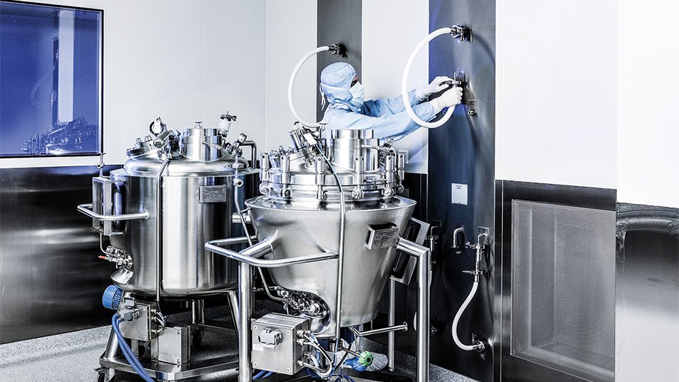 Person arbeitet an Edelstahlbehälter im Labor