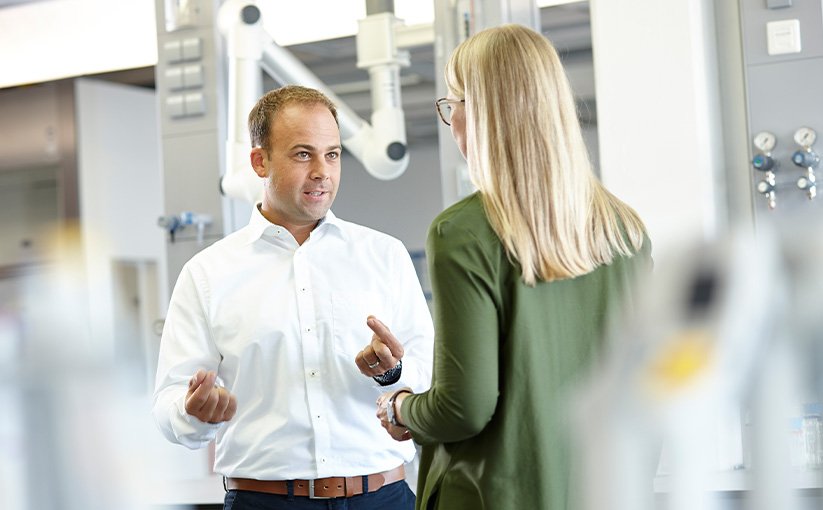 Person in white shirt talking to another person in laboratory setting