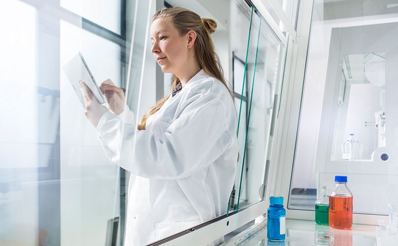 Laboratory worker with an iPad in front of a fume hood