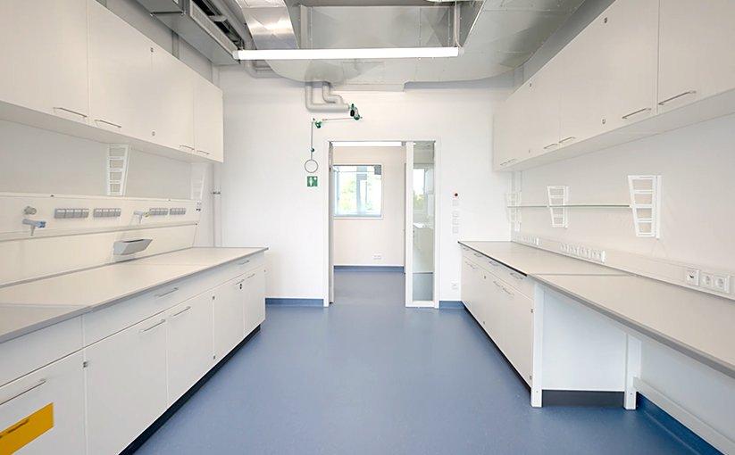 Empty laboratory room with workbenches and cabinets.