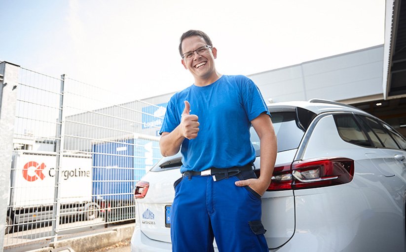 Service technician in front of vehicle gives thumbs up