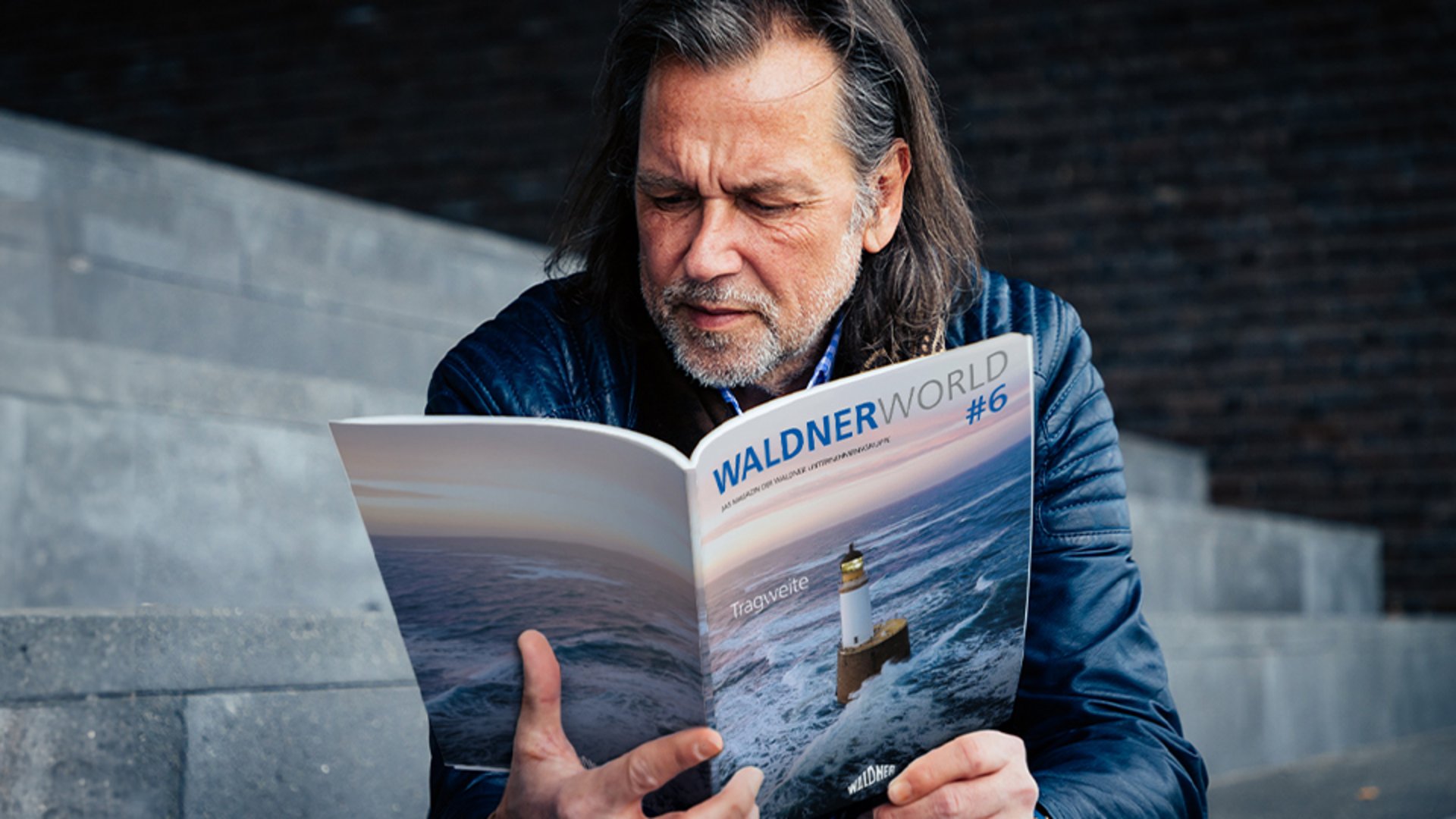 Mann sitzt auf Treppe und liest das Waldner World Magazin