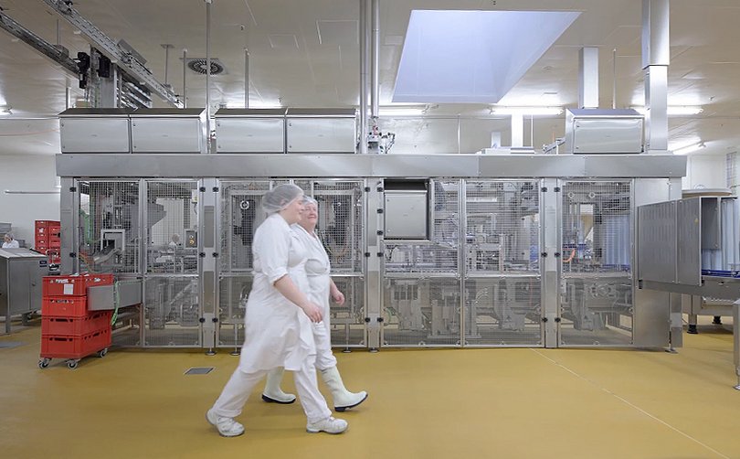 Rügenwalder Mühle employees in front of a longitudinal runner machine