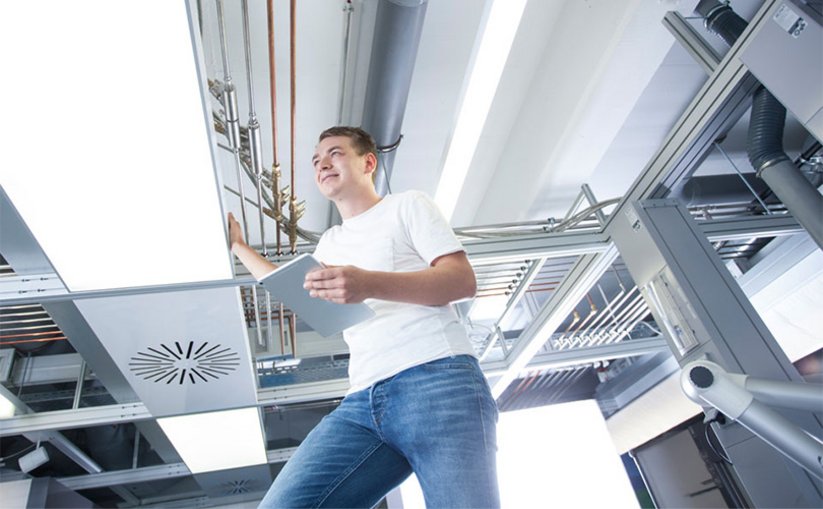 Techniker arbeitet an moderner Gebäudetechnik oberhalb der Decke.