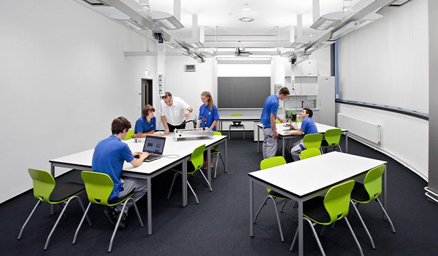 Students collaborating in a classroom with modular tables and green chairs