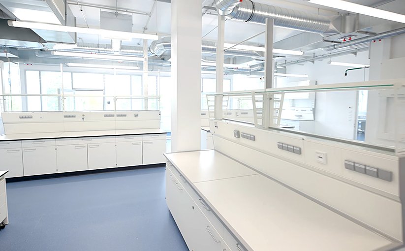Bright laboratory room with work islands and ventilation ducts.