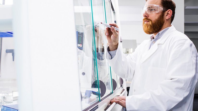 Laboratory worker in front of inclined sash of a fume hood