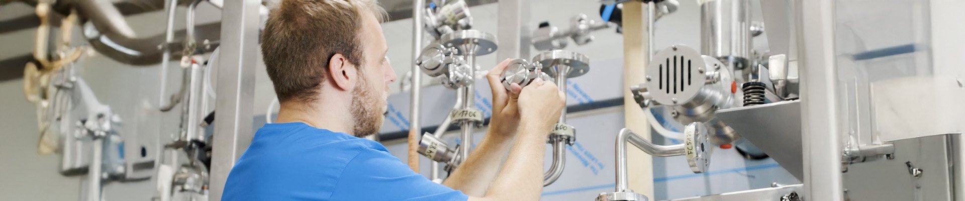 Person arbeitet an komplexer Rohrleitung