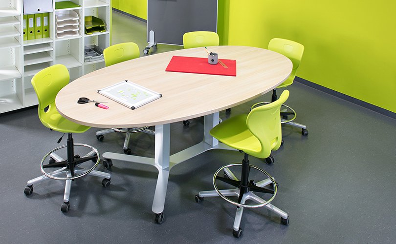 Oval collaboration table with yellow chairs in classroom