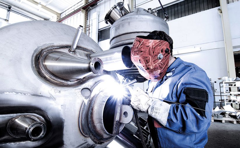 Welder wearing a helmet welding a pressure vessel