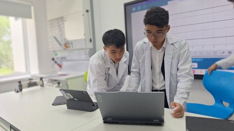 Zwei Schüler arbeiten gemeinsam an einem Laptop in einem hellen Labor
