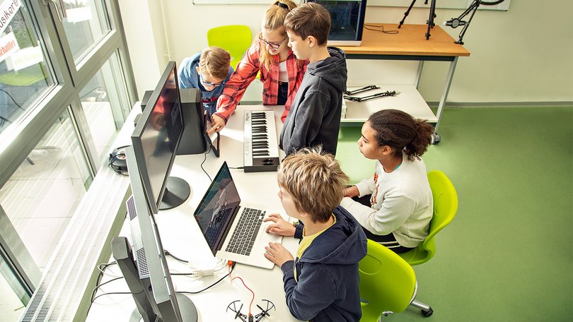 Group of students working together on laptops and electronics